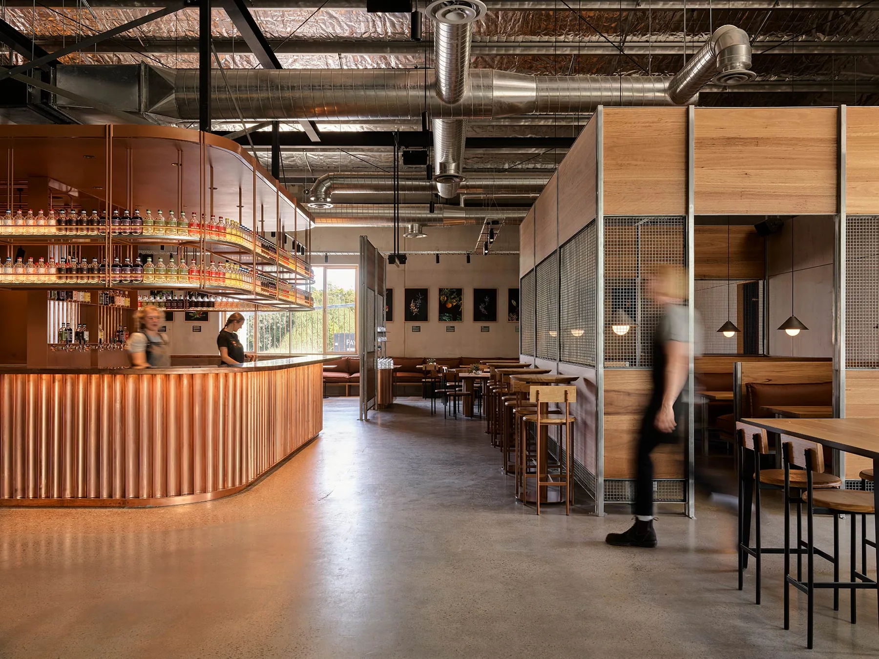A fluted copper bar curving through the room, with exposed ductwork above and timber booths beyond