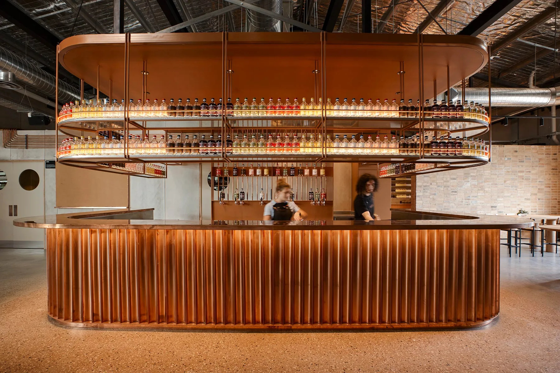 The copper-clad circular bar at Four Pillars, a ring of backlit bottles suspended above it