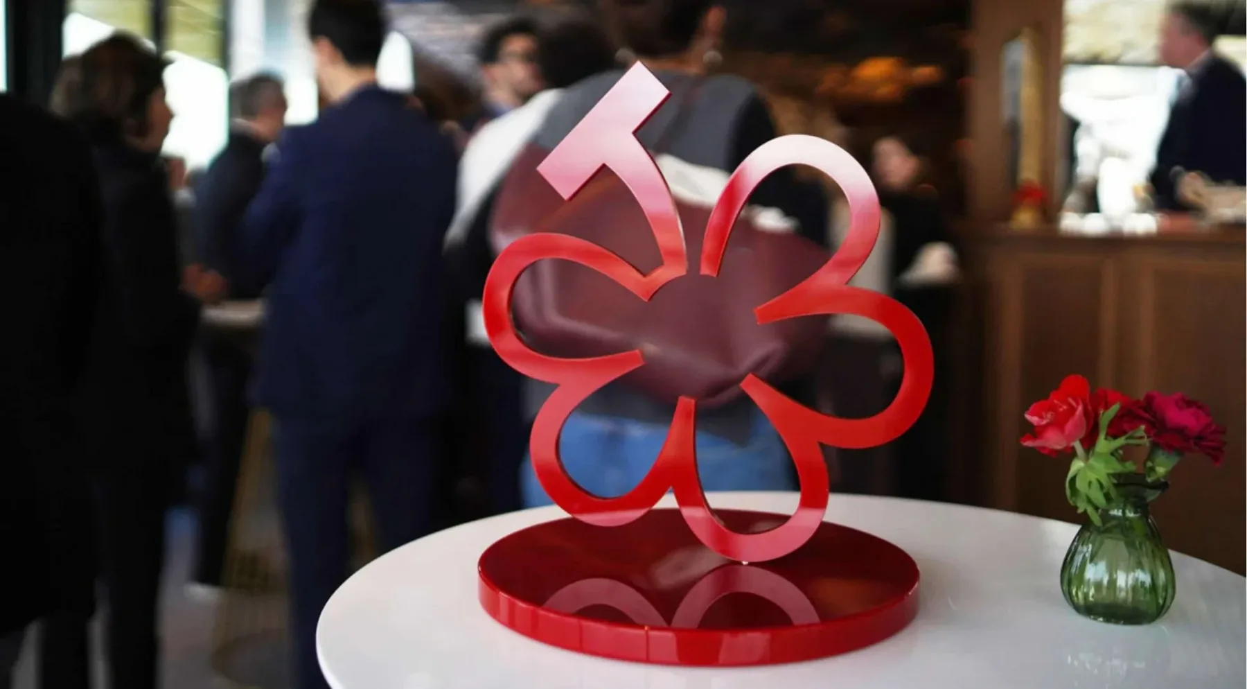 The Michelin Guide Grapes emblem, a red five-petalled flower with a stem, displayed on a table at the Dijon announcement