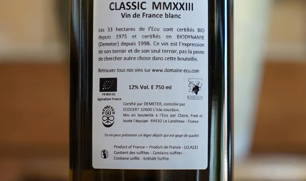 The back label of a Domaine de l’Écu bottle stating the estate has been certified organic since 1975 and Demeter biodynamic since 1998, carrying the EU organic leaf, the Demeter mark and the Biodyvin mark
