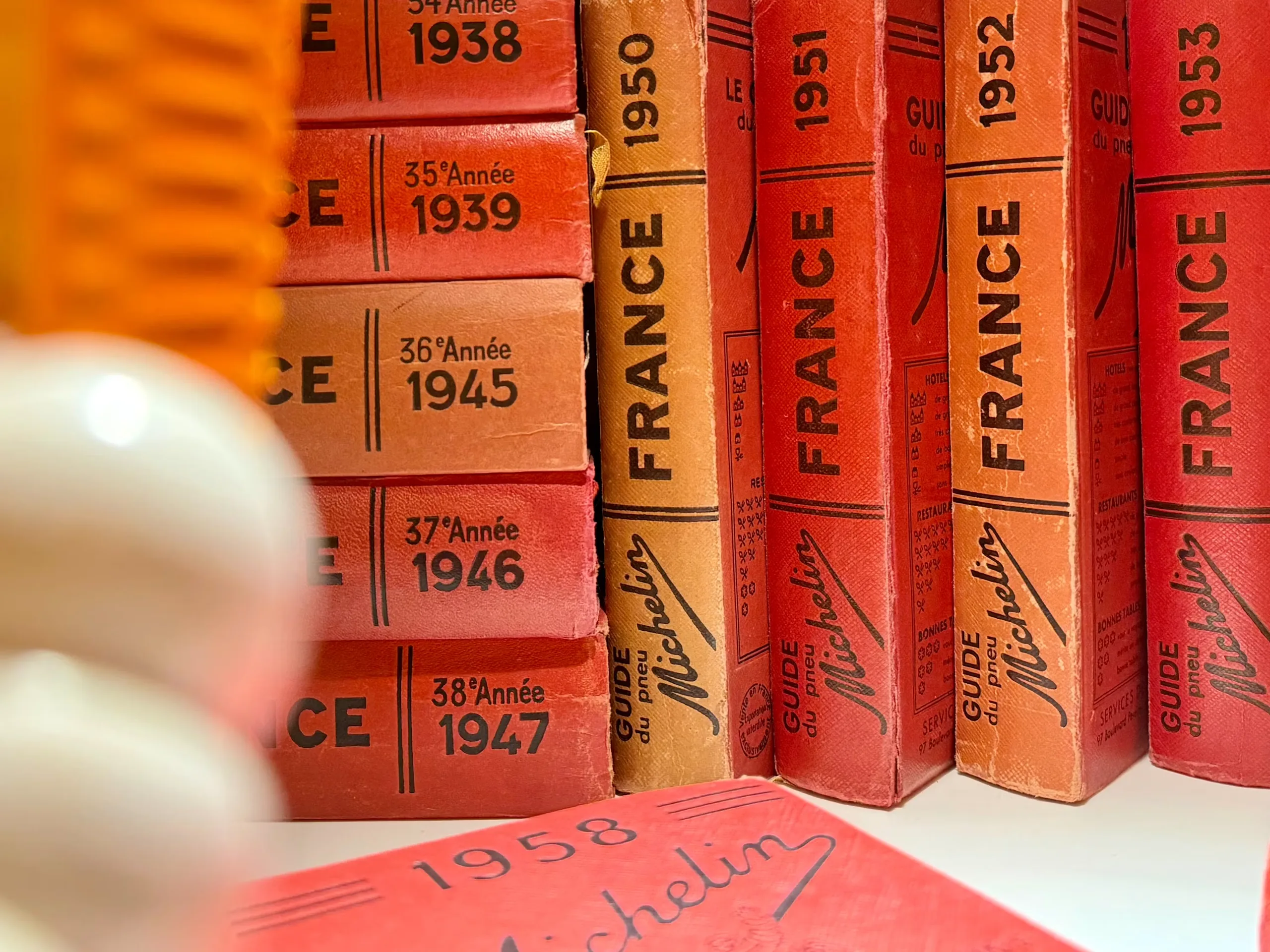 A shelf of red Michelin France guides, spines dated from 1938 to 1958
