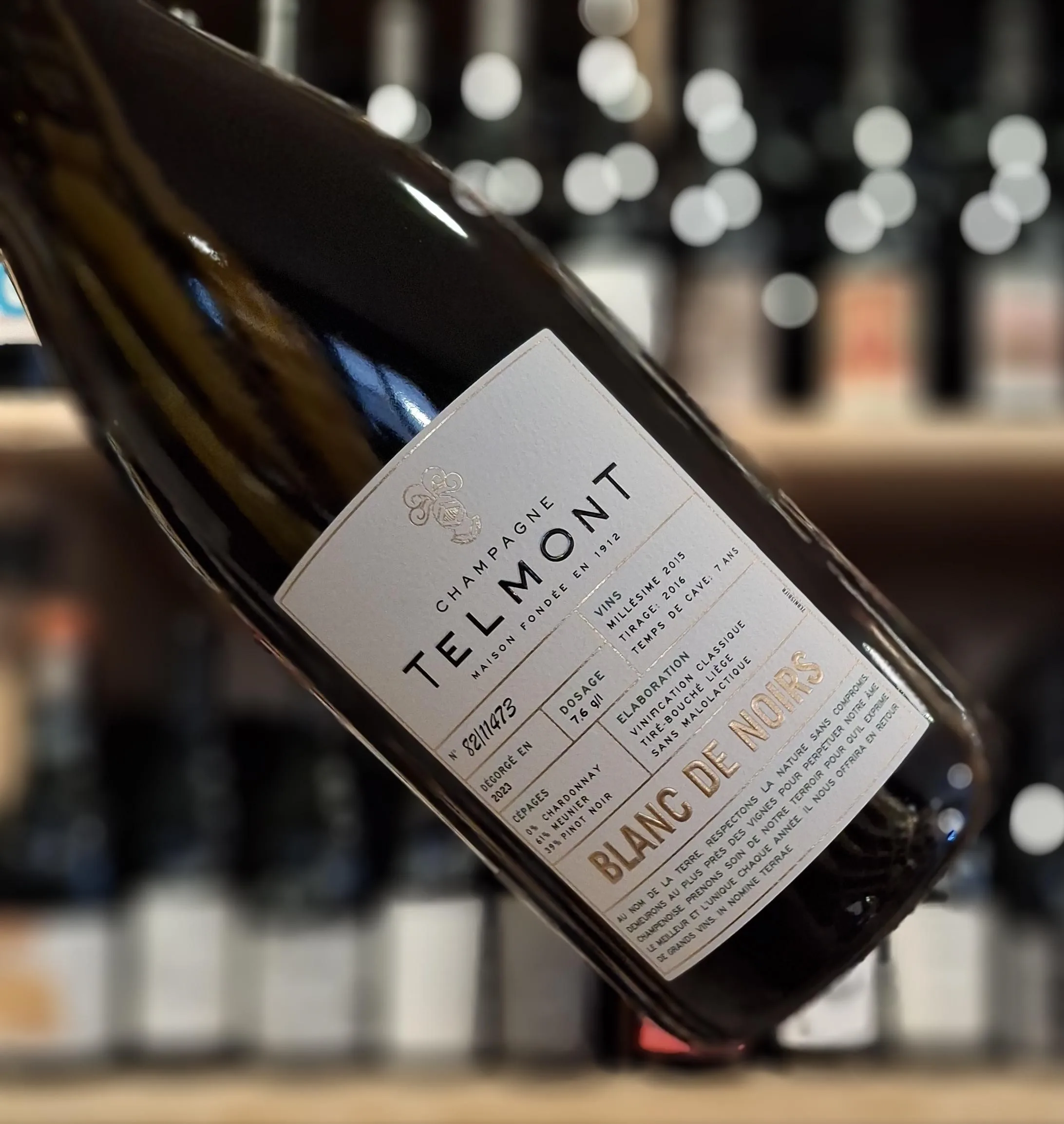A bottle of Telmont Blanc de Noirs held at an angle, its label reading Maison fondée en 1912, millésime 2015, dosage 7.6 g/l