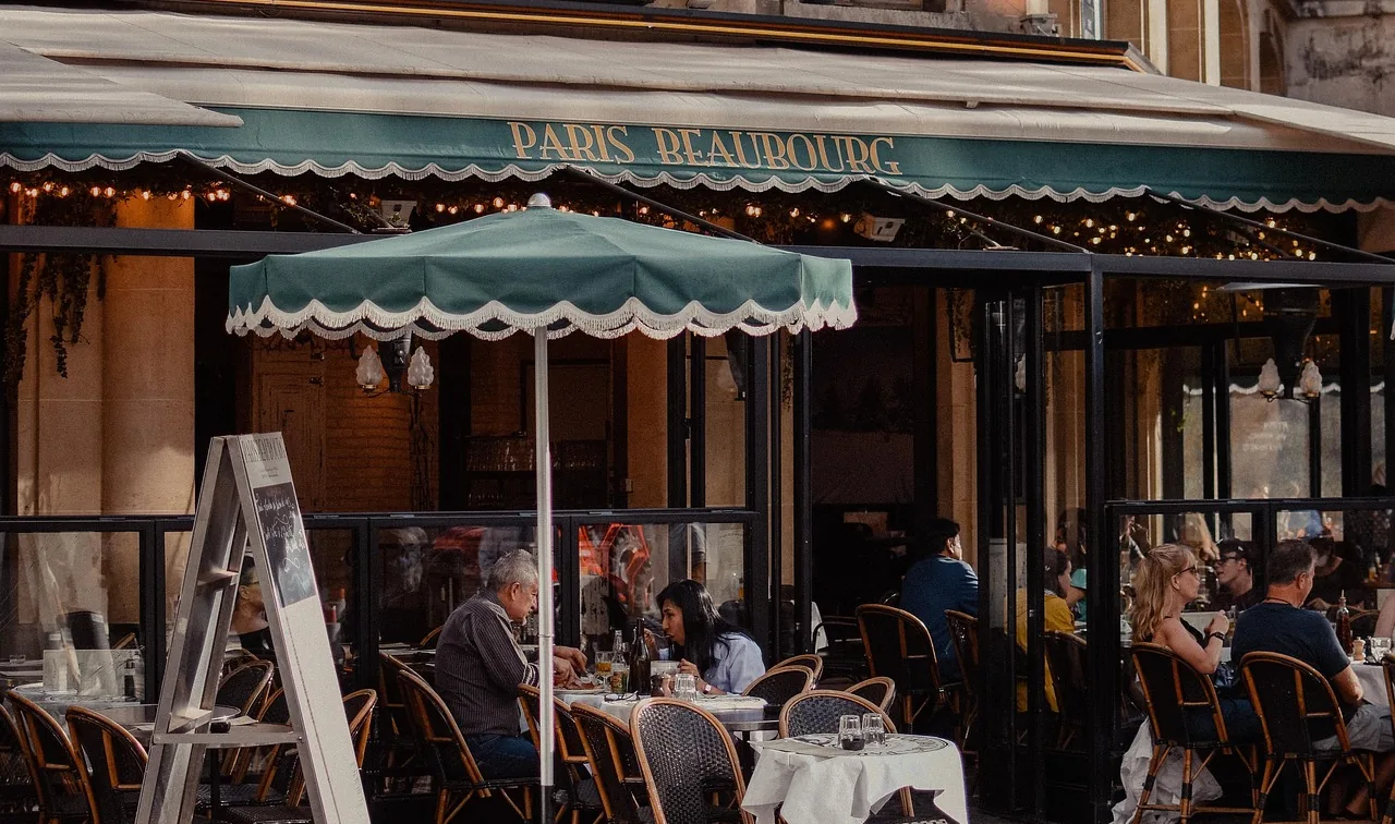 Diners at a café terrace under a green awning