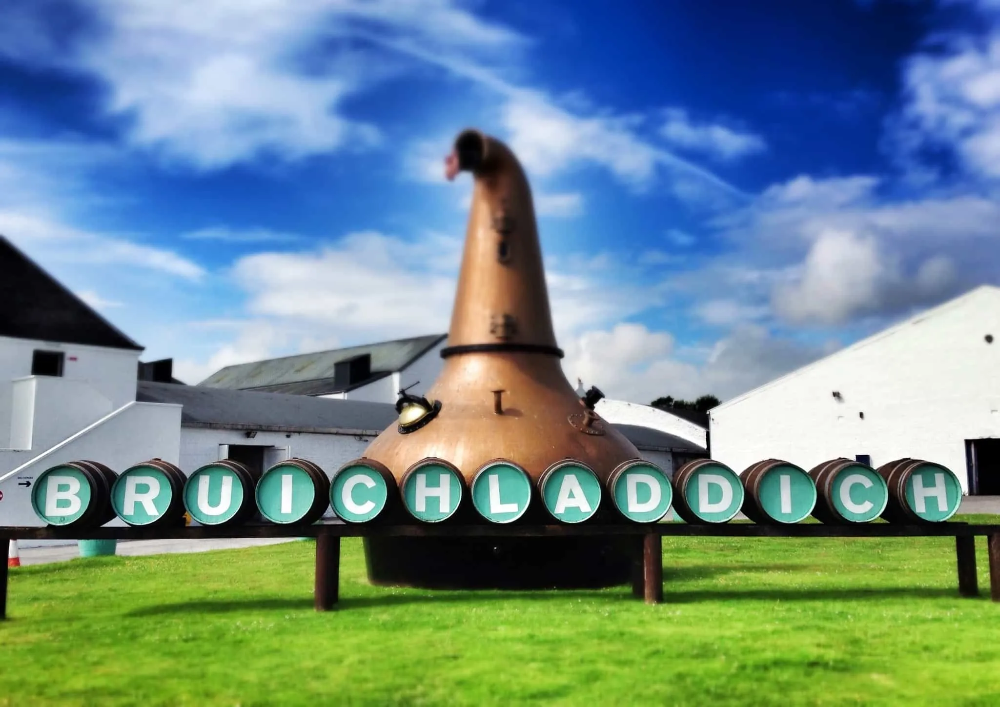 A copper pot still behind a Bruichladdich sign spelled out on barrel ends