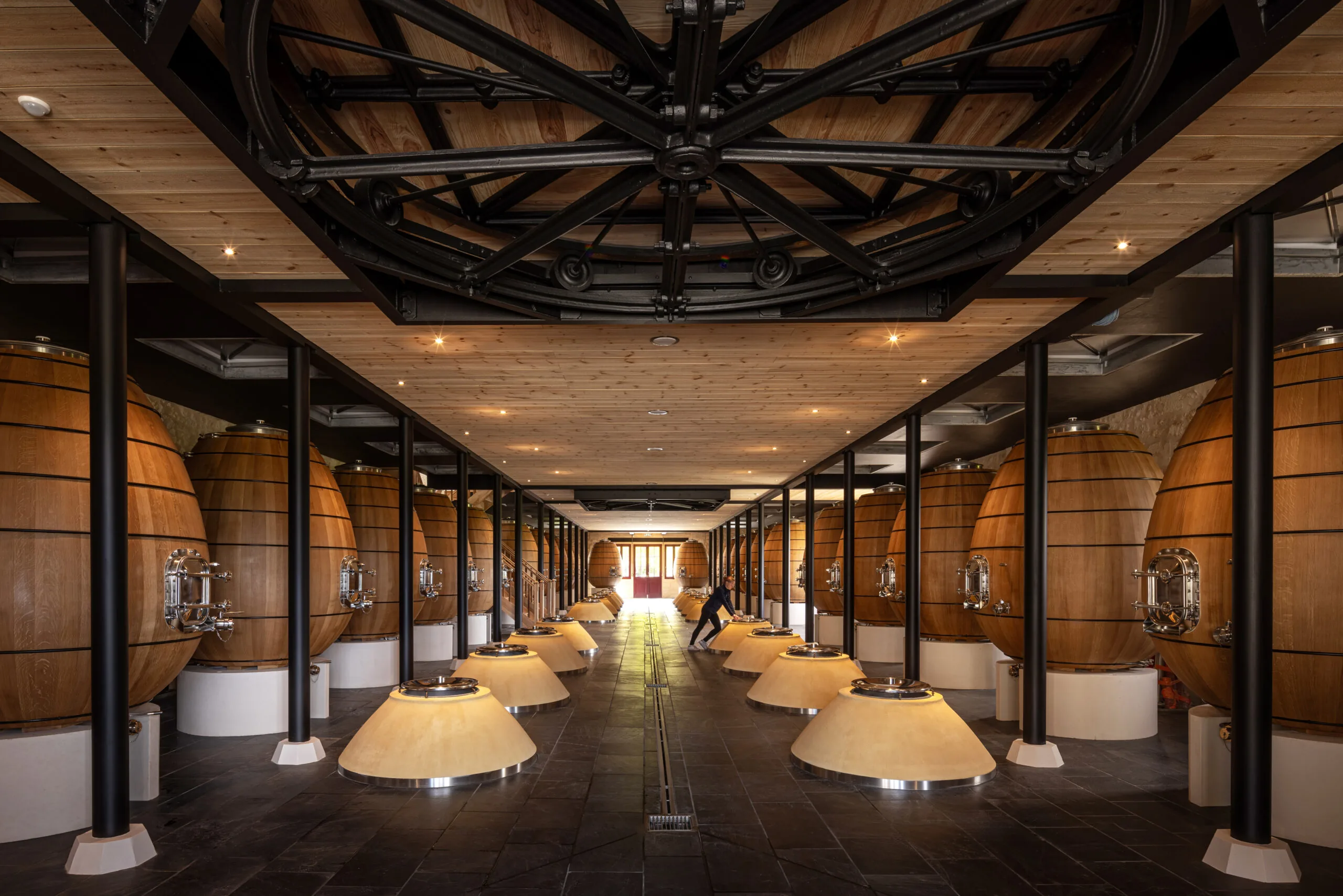 Rows of large oval wooden vessels in a casking cellar at Château Pontet-Canet
