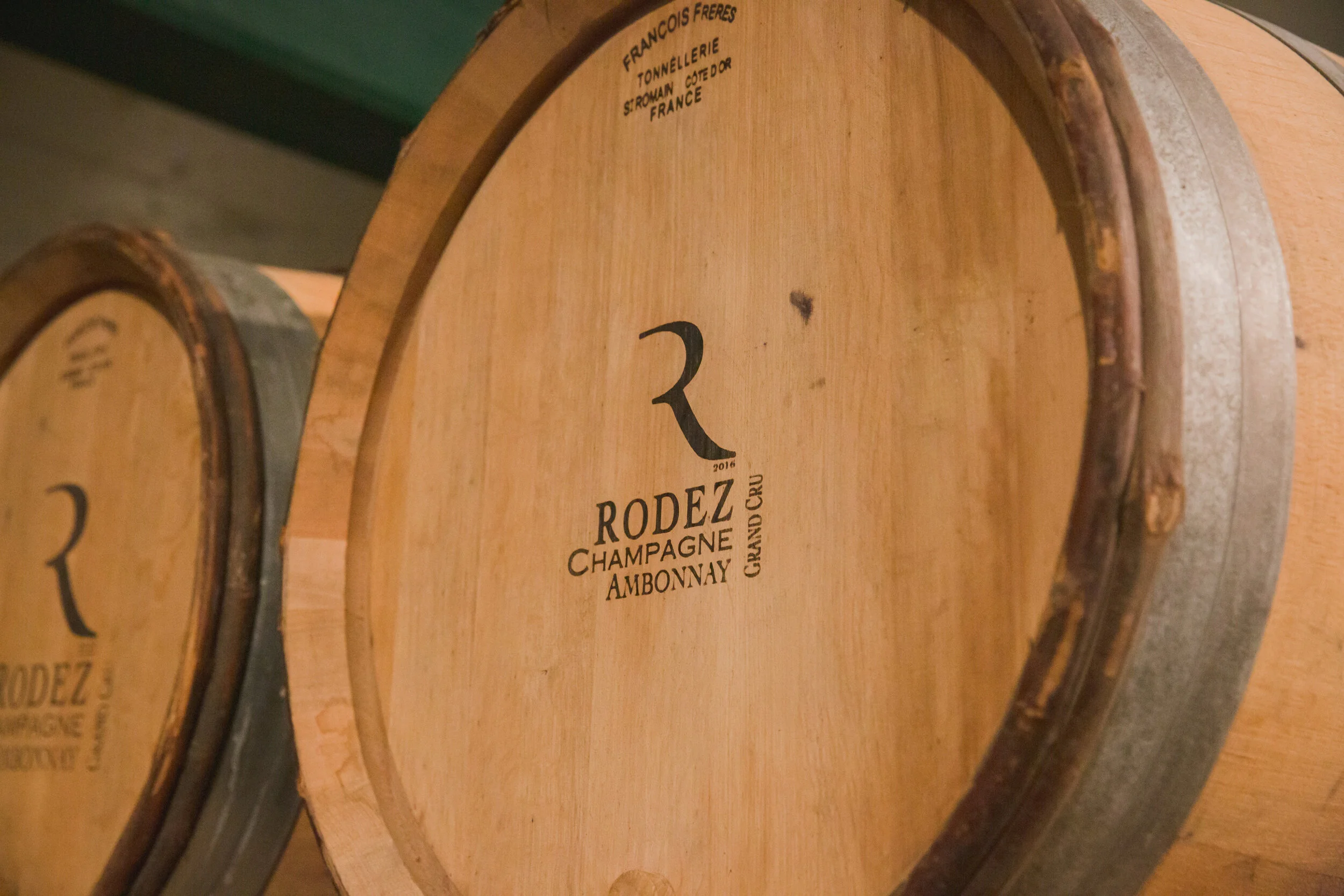 The head of an oak barrel branded Rodez Champagne Ambonnay Grand Cru, with a second branded barrel beside it