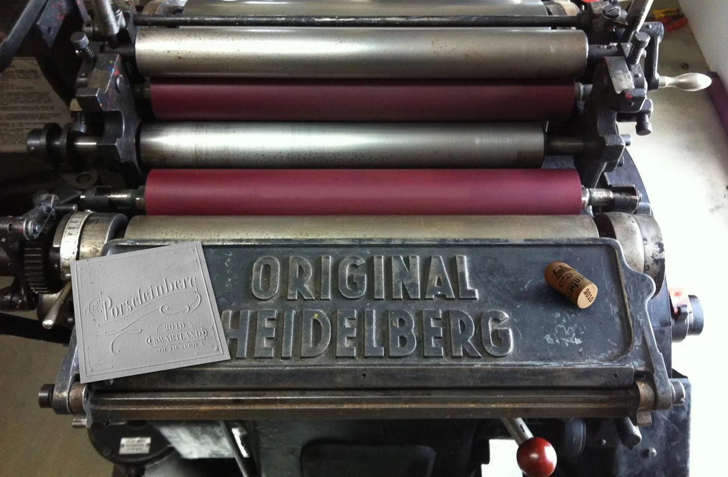An Original Heidelberg printing press with an embossed Porseleinberg 2010 Swartland label and a branded cork resting on it