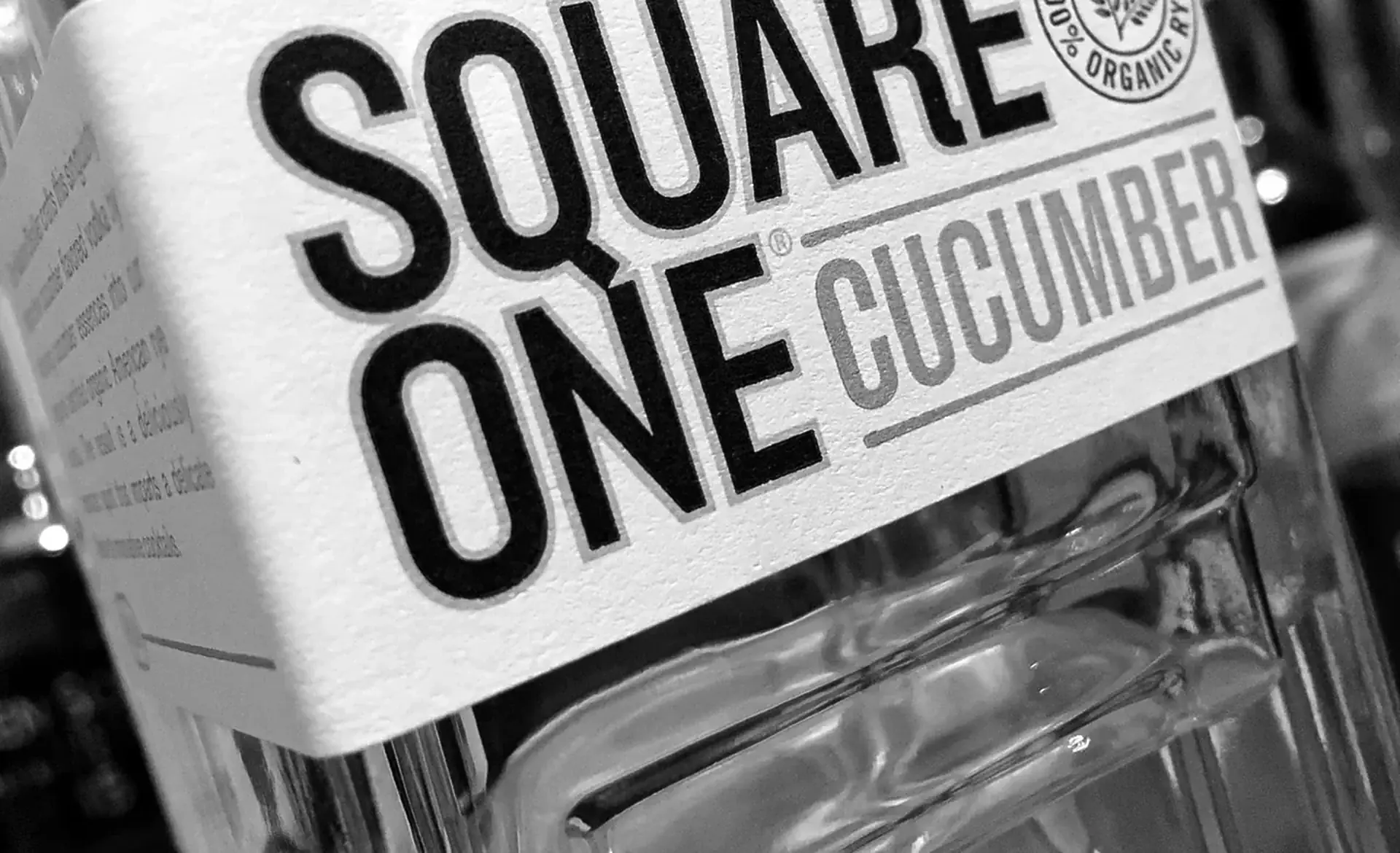 Black-and-white close-up of a Square One Cucumber label on a clear square glass bottle