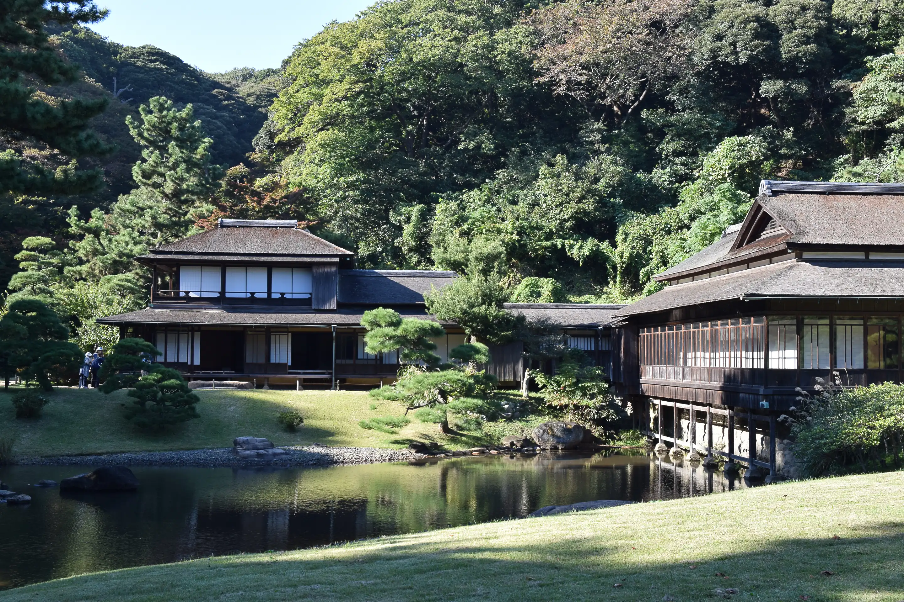 Rinshunkaku villa at Sankeien garden in Yokohama, its timber wings over a pond below a wooded hill