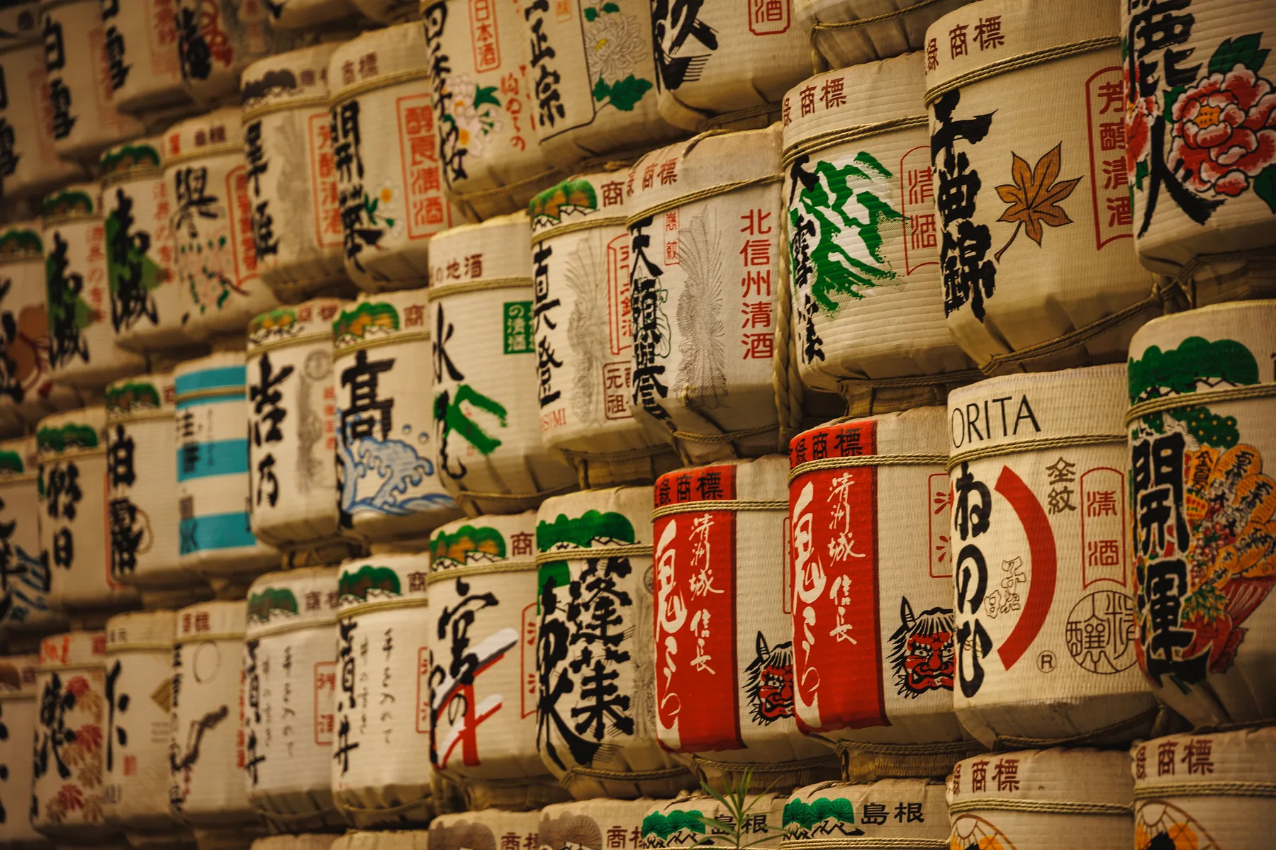 Wall of straw-wrapped kazaridaru sake barrels painted with brewery marks